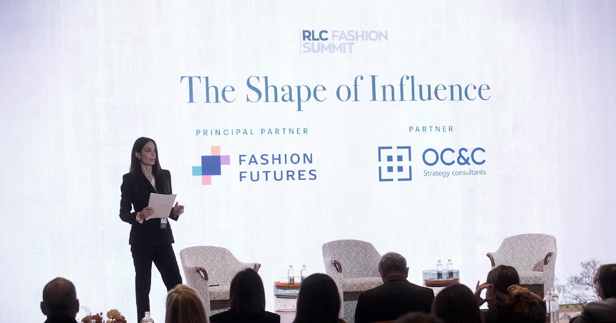Councillor Debora Massari of Regione Lombardia speaks on stage at the 2026 RLC Fashion Summit with partner logos displayed on screen.