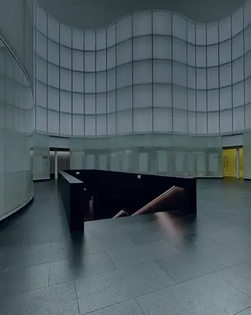 A modern interior with curved, white panel walls and a dark staircase leading down.