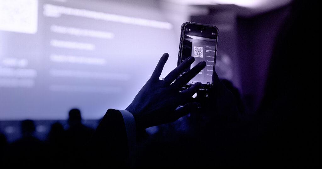 Audience member participating in a real-time poll with a smartphone during the RLC Fashion Summit in Milan.
