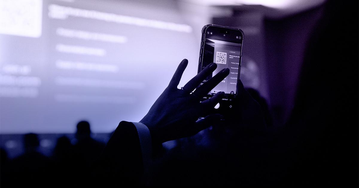 Audience member participating in a real-time poll with a smartphone during the RLC Fashion Summit in Milan.
