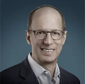 David R. Jaffe – Chairman & CEO, Ascena Retail Group | RLC Global Forum Portrait of David R. Jaffe, Chairman & CEO of Ascena Retail Group, wearing glasses, a light blue shirt, and dark jacket, smiling against a blue background.