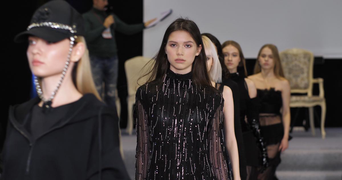 Models dressed in black walking across the catwalk during a fashion week stage show.