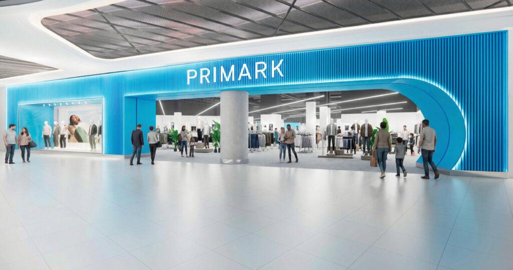 Primark store entrance inside a shopping mall, featuring a bright blue storefront with the brand logo and shoppers walking past. displays