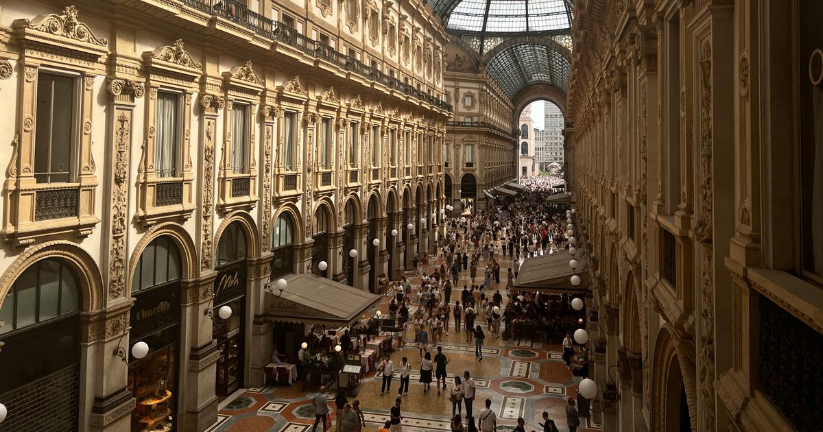 Interior view of the Galleria Vittorio Emanuele II in Milan, filled with tourists, shoppers and luxury stores.