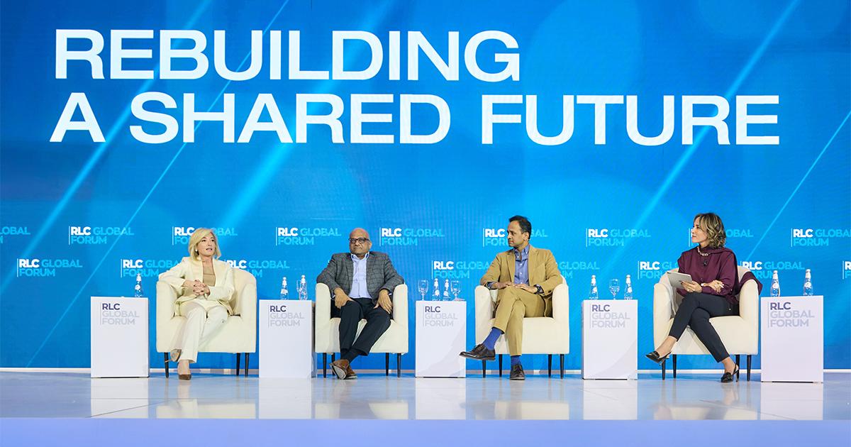 Four panel discussion speakers sitting in armchair seats on a stage under a blue backdrop reading Rebuilding A Shared Future at RLC Global Forum.