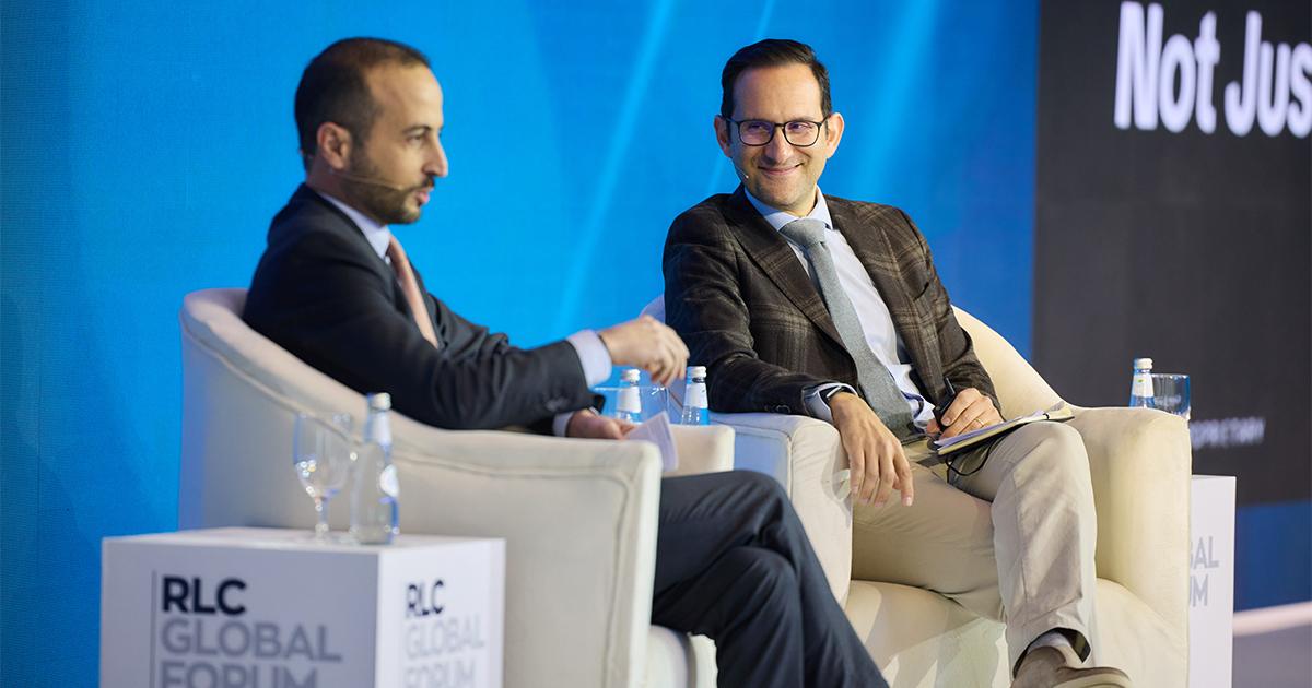 Four panel discussion speakers sitting on stage engaging in a presentation during a session at RLC Global Forum.