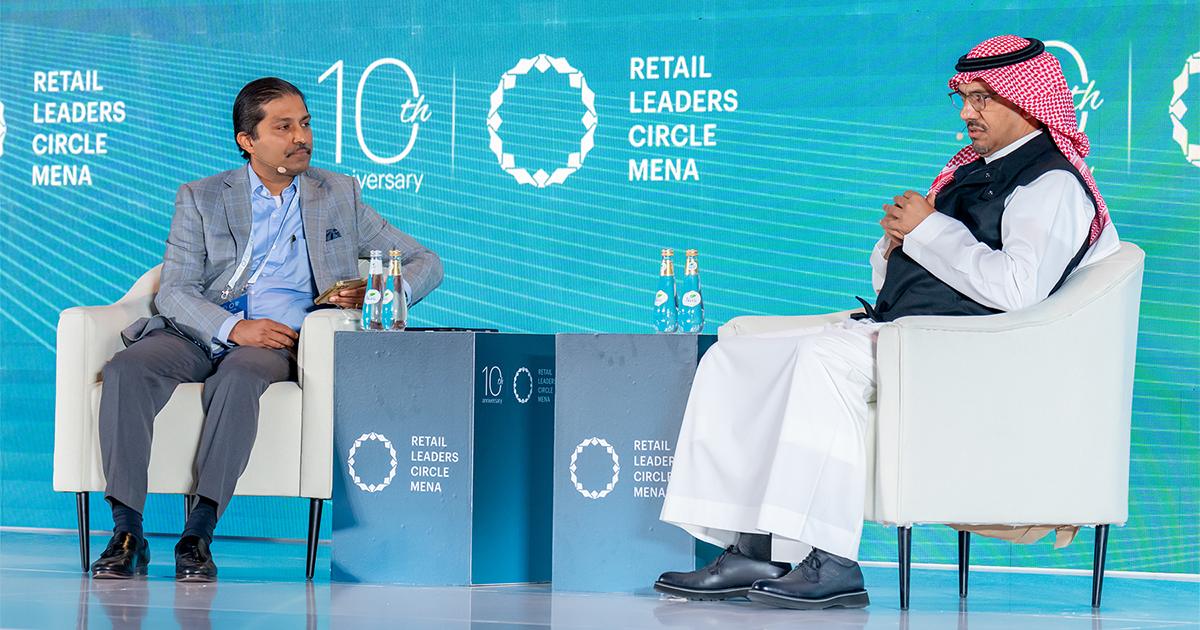 Two male executives in a fireside chat on stage surrounded by RLC Global Forum 10th Anniversary branding.