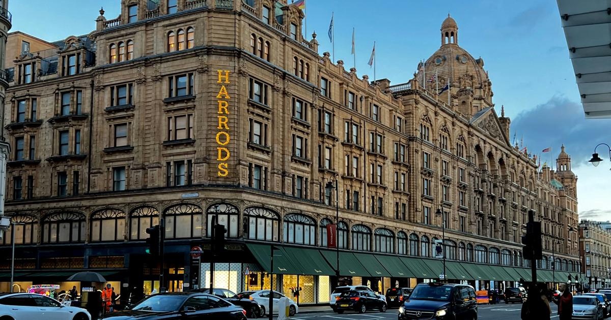 The Harrods department store building in Knightsbridge, London, with traffic visible on the street.