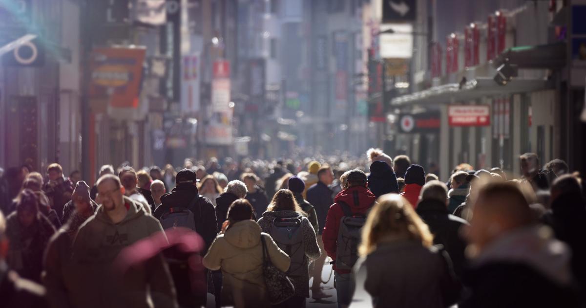 Crowds of pedestrians walking along a busy city shopping street in Europe.