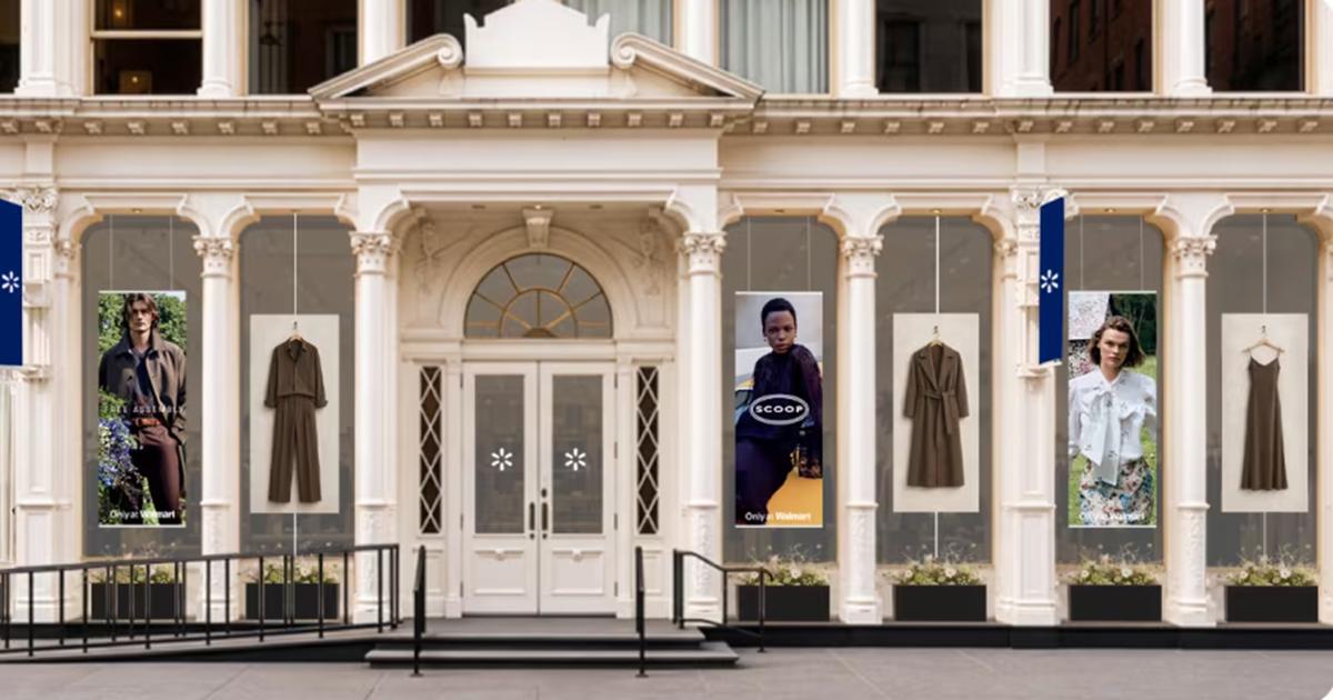 Storefront display featuring Walmart fashion brand posters and suspended clothing against an ornate white facade.